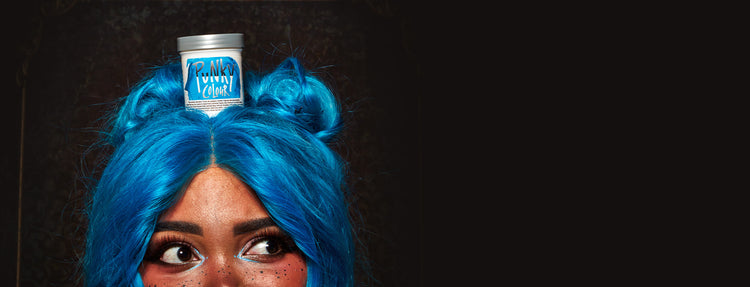 Person with blue hair wearing a can of Punky Colour Semi-Perm on their head against a black background