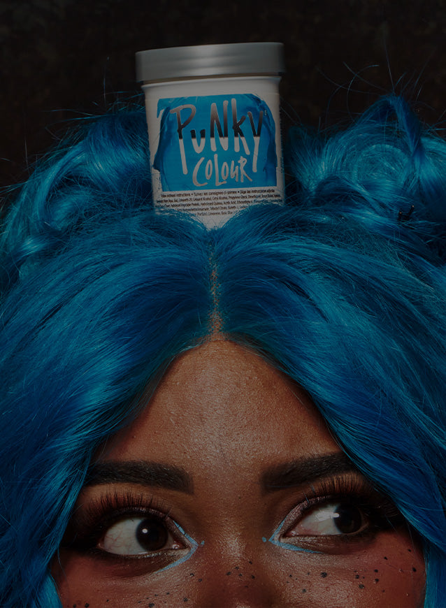Person with blue hair wearing a can of Punky Colour Semi-Perm on their head against a black background