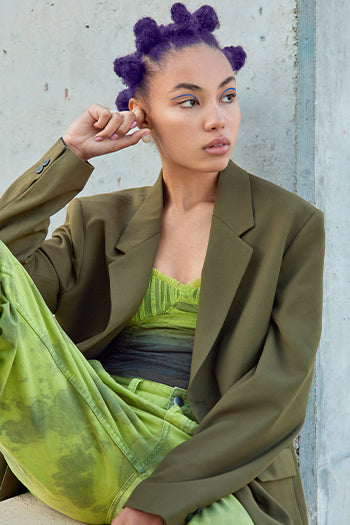 Model with Purple Bantu Knots – Stylish model with purple bantu knots, wearing an olive blazer and neon green outfit.