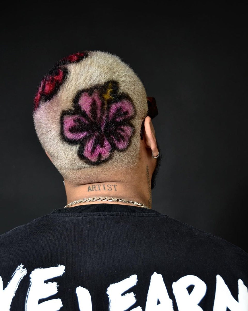 Creative Hair Art with Floral Design on Shaved Head – Vibrant pink flower design on a platinum shaved head, showcasing bold hair artistry.