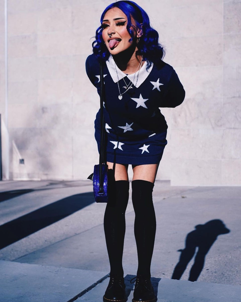 Woman with Midnight Blue Hair - Fashionable woman with vibrant midnight blue curly hair, wearing a star-print sweater, posing confidently.