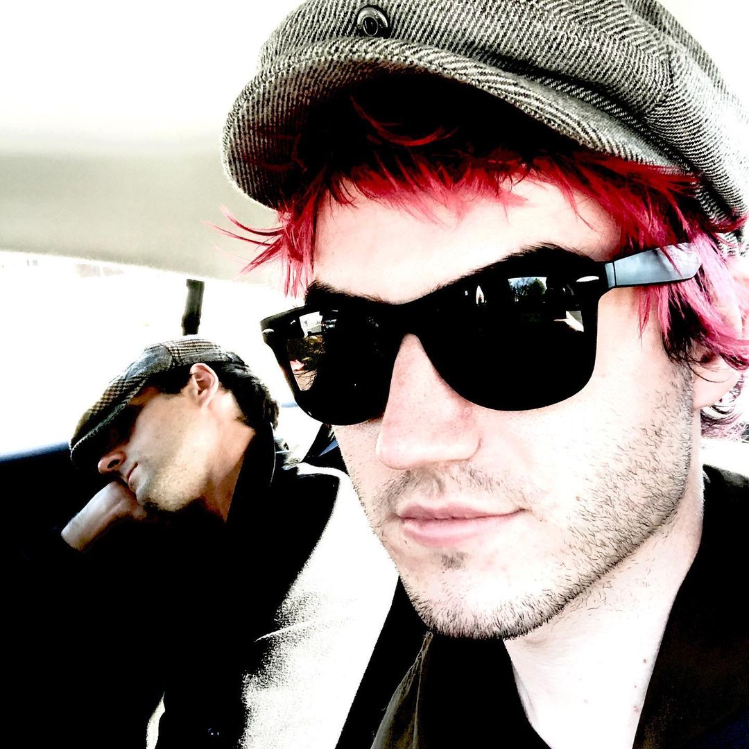 Man with short vibrant red hair in sunglasses – Edgy, punk-inspired red hair styled with a casual look for standout fashion.