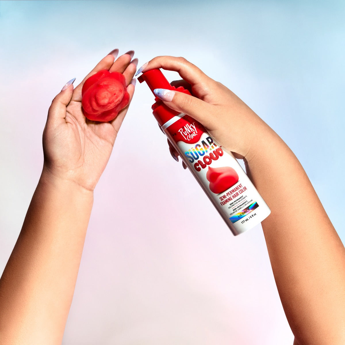 Aerial shot of a right hand holding a sugar cloud licorice bottle, with a red hair color foam in the left hand