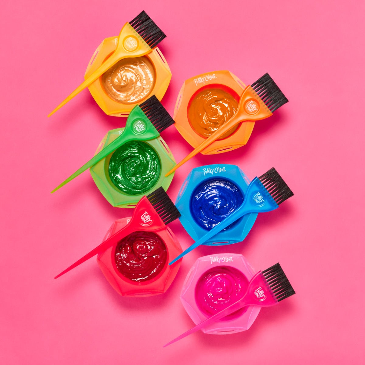 Six Hair Dye Bowls with Brushes on Pink Background – A rainbow set of hair dye bowls and brushes filled with vibrant colors.