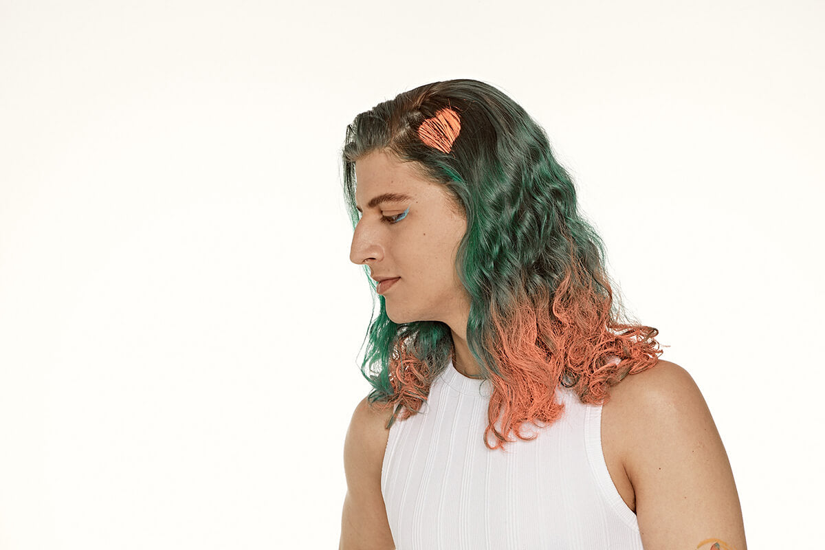 Punky Colour Tiger Orange hair spray side view – A close-up of a model's wavy green hair enhanced with vibrant Tiger Orange highlights.