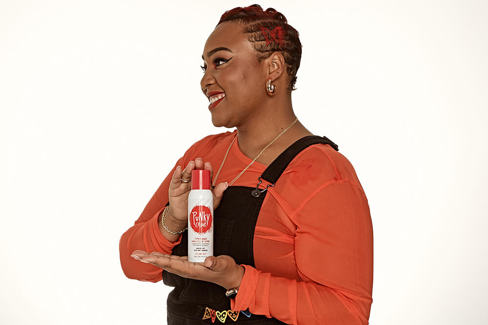 Punky Colour Cougar Red spray showcase – A woman holding a red hair spray can with a smile, featuring styled short red-dyed hair.