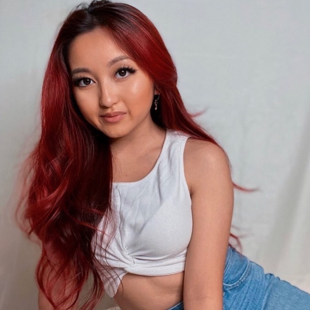 Woman with deep red hair posing – A woman with long, deep red hair styled in waves, showcasing vibrant hair color transformation.